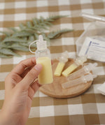 A person holding a Haakaa Silicone Colostrum Collector full of milk, in their hand with other Silicone Colostrum Collectors blurred in the background