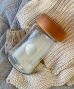 Hevea Wide Neck Glass Baby Bottle with Natural Rubber Cap on a white knitted blanket.