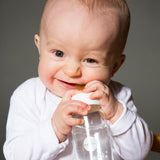 Baby biting down on a 100% natural rubber bottle nipple by HEVEA.