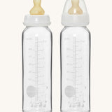 Hevea Glass Baby Bottles Standard Neck 2 Pack - 240ml, one with a dust cap, the other without.