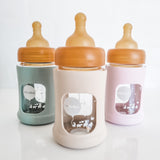 Hevea Glass Baby Bottle Wide Neck With Rubber Sleeve - 150ml in Seafoam Blue, Sand and Powder Pink