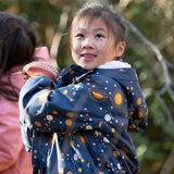 Child in a forest wearing a Little Green Radicals Waterproof Winter Coat with a cosy fleece hood, made from recycled bottles and a cosy polyester fleece, in a navy Night Moon print, available now at Babipur.