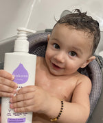 A close up of a baby holding the Kokoso unscented organic baby body and hair wash 200ml bottle. Bottle available at Babipur.