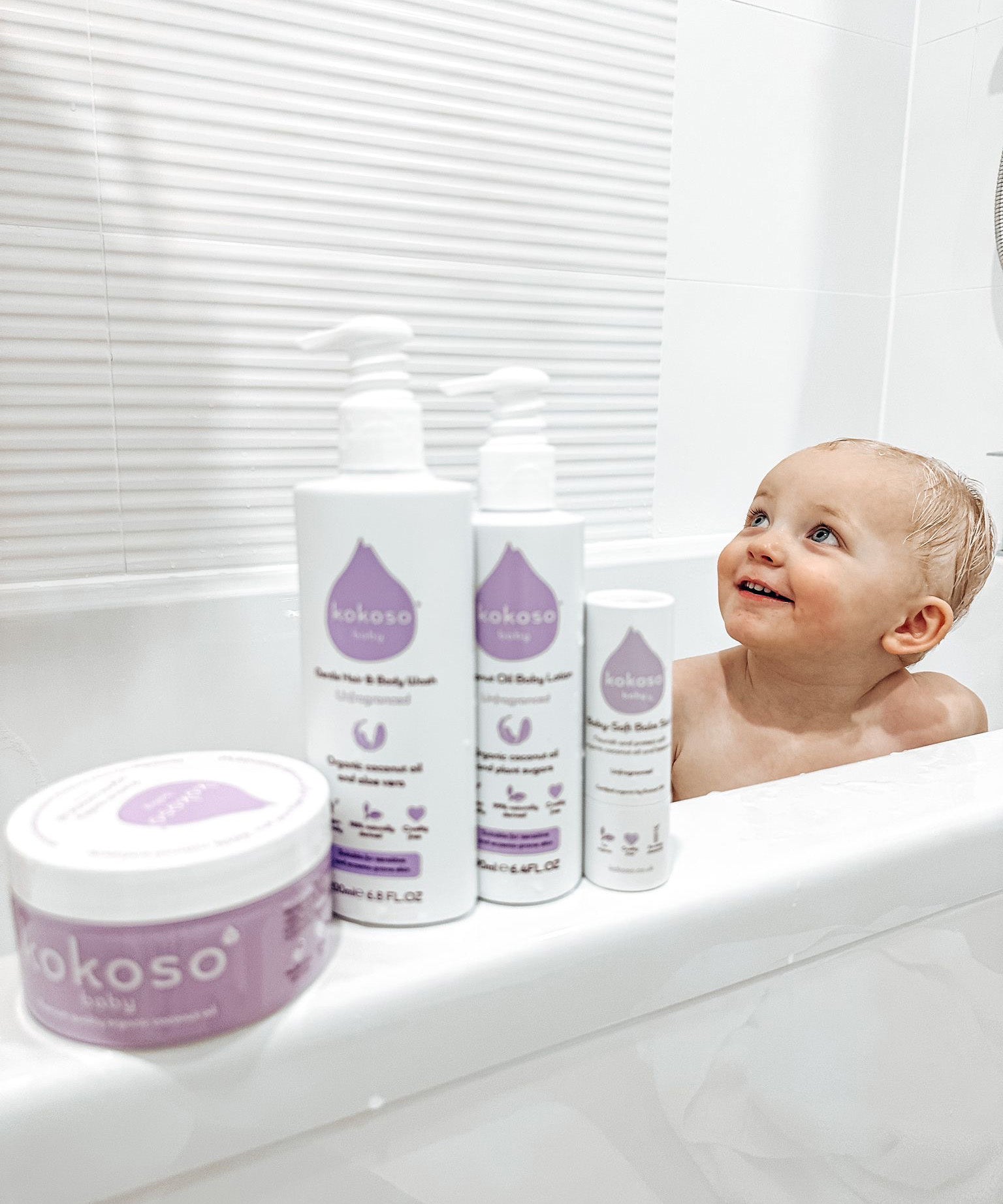 Kokoso unscented organic baby body and hair wash 200ml bottle standing on the side of the bath next to the baby lotion, balm and coconut oil, all are available at Babipur.