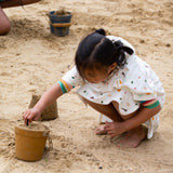 A child making sand castles, whilst wearing the LGR Adventure Hooded Beach Towel Poncho