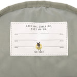 A close up of the Lassig kids mini caramel happy print backpack showing the white name tag on the inside