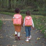 Two kids walking through a forest and wearing the Lassig kids mini adventure backpack in rose