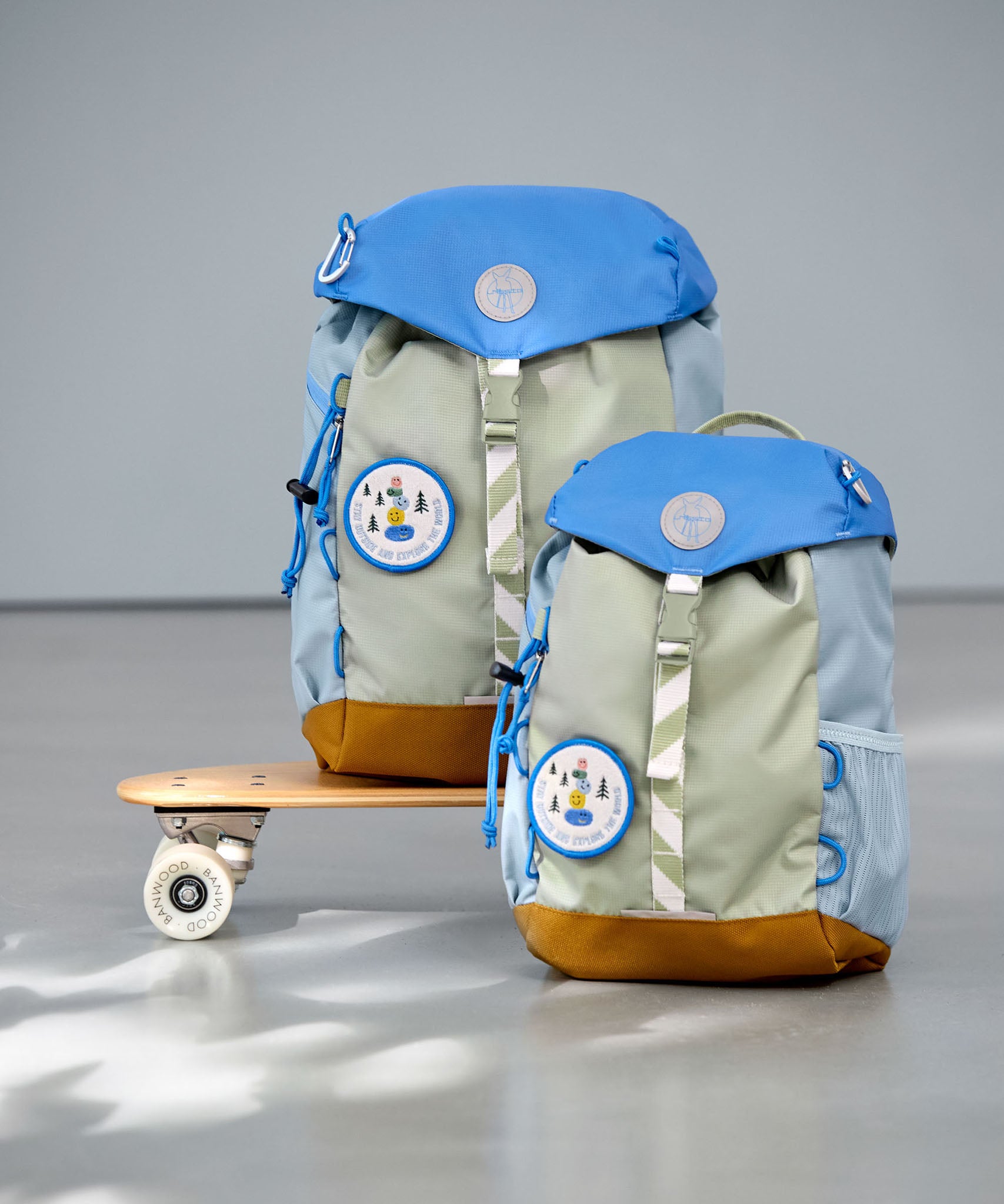 2 Lassig kids mini outdoor backpack in sunny explorer green on a mini skateboard