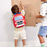 A child drawing on paper in a playroom and wearing the Lassig kids tiny fire engine backpack