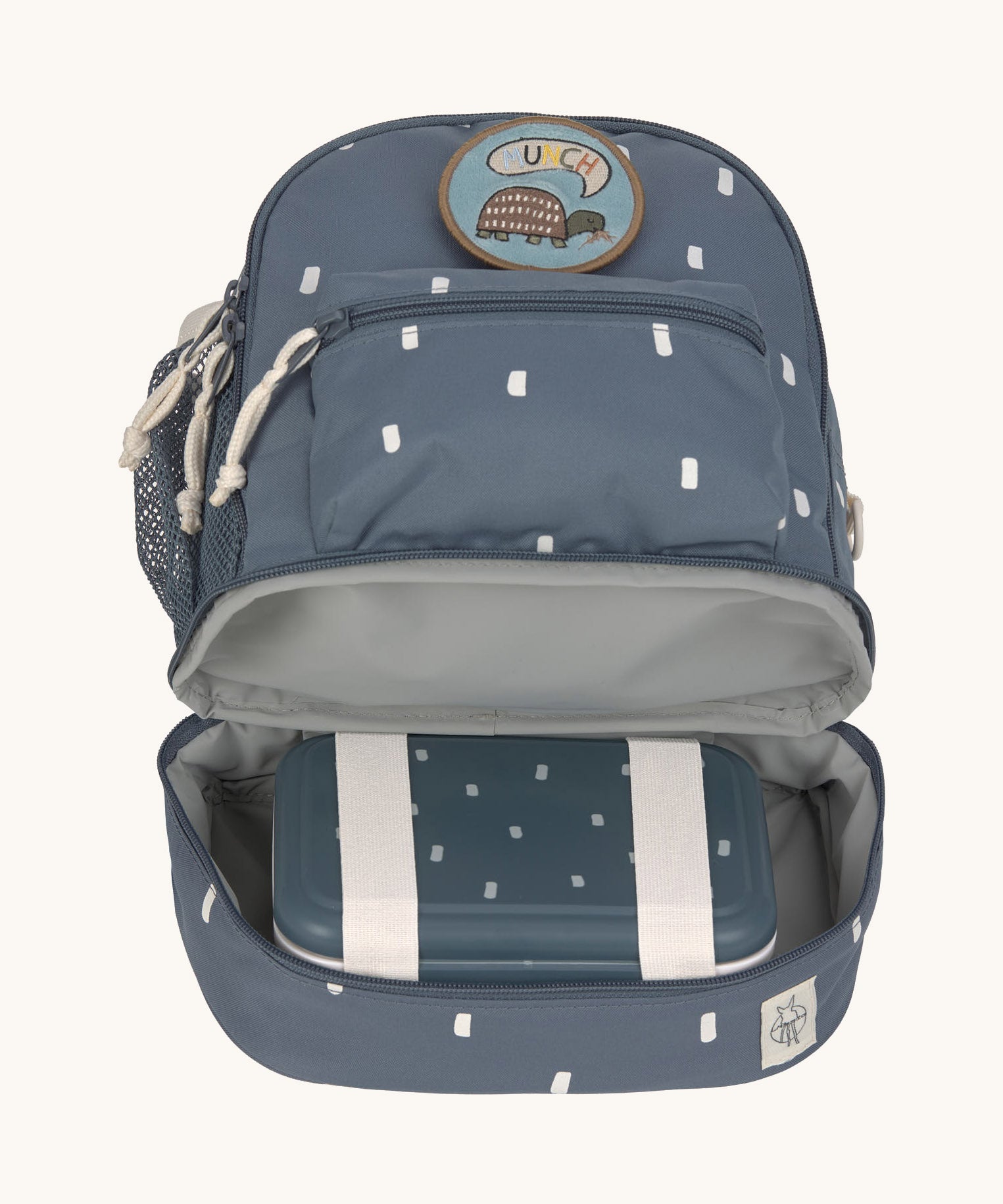 The inside of the Lassig kids mini midnight blue happy print backpack showing a lunchbox inside the bottom compartment.