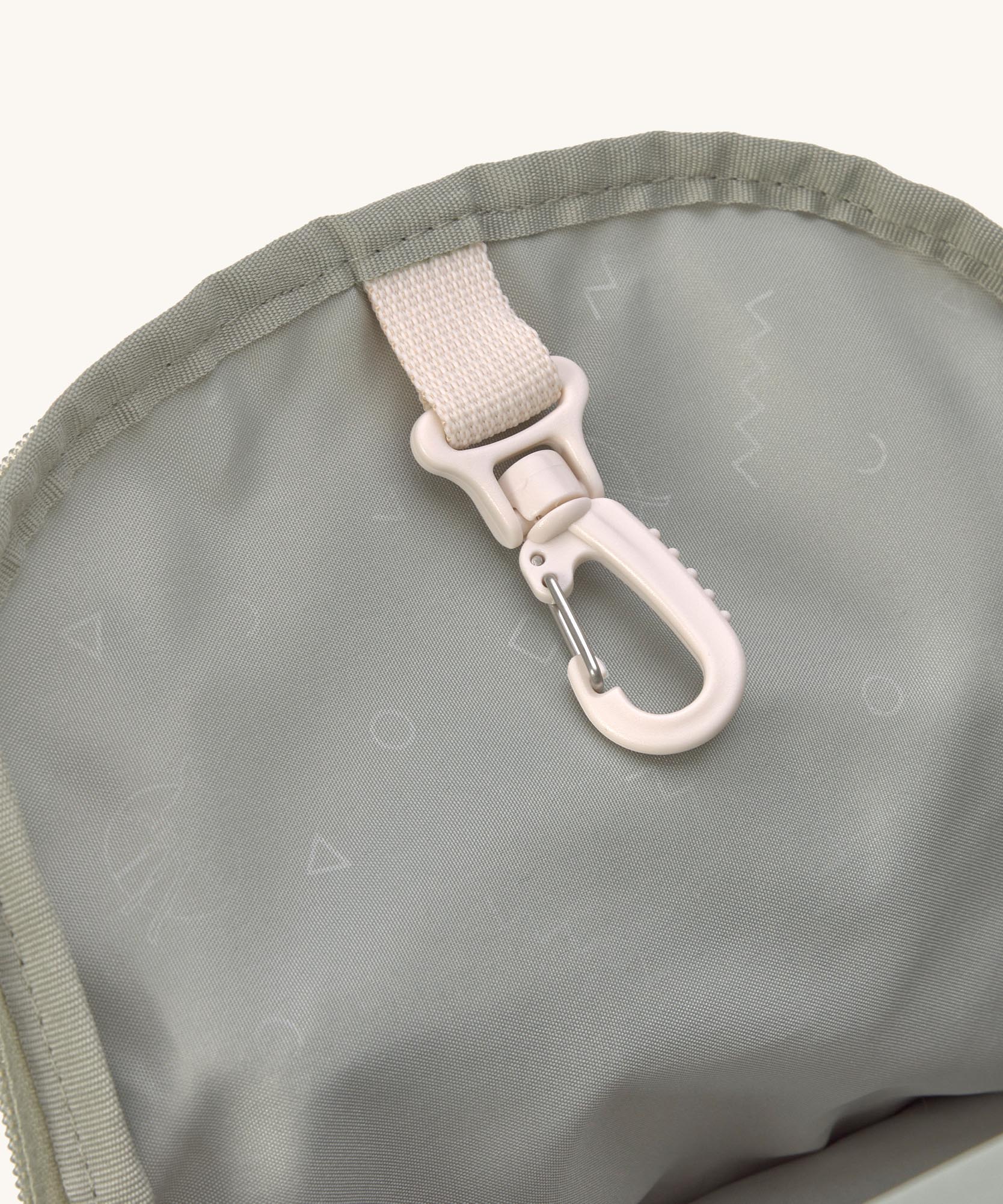 A close up of the Lassig kids mini olive happy print backpack showing the handy clip on the inside