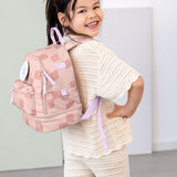 A child posing and wearing the Lassig kids mini pattern party rose pattern backpack.
