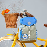 Lassig kids mini outdoor backpack in sunny explorer green hanging on a yellow bicycle.