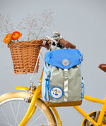 Lassig kids mini outdoor backpack in sunny explorer green hanging on a yellow bicycle.