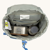 The inside of the Lassig kids mini outdoor backpack in sunny explorer green showing the room inside the main compartment. Features a blue toggle for closing the compartment
