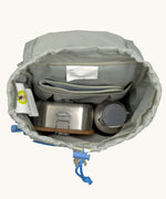 The inside of the Lassig kids mini outdoor backpack in sunny explorer green showing the room inside the main compartment. Features a blue toggle for closing the compartment