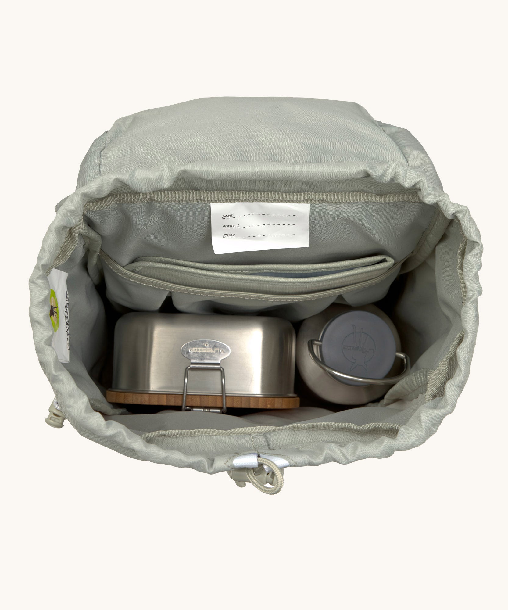 The inside of the Lassig kids mini outdoor backpack in sunny explorer pink showing the room inside the main compartment. Features a blue toggle for closing the compartment