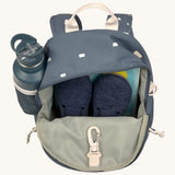 The inside of the Lassig kids mini midnight blue happy print backpack showing various items  inside the main compartment with a bottle in the mesh side pocket