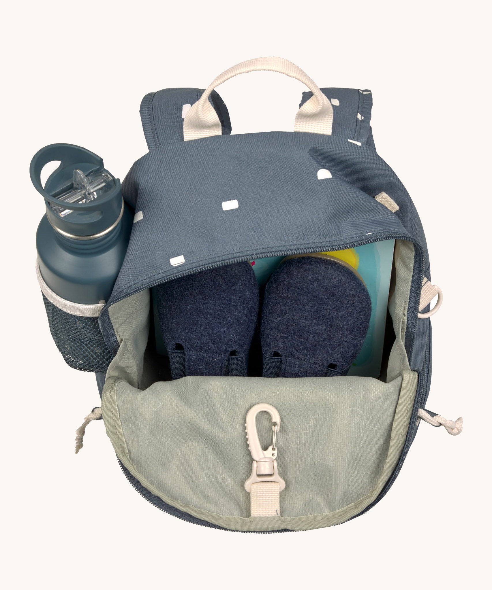 The inside of the Lassig kids mini midnight blue happy print backpack showing various items  inside the main compartment with a bottle in the mesh side pocket