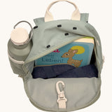 The inside of the Lassig kids mini olive happy print backpack showing various items  inside the main compartment with a bottle in the mesh side pocket