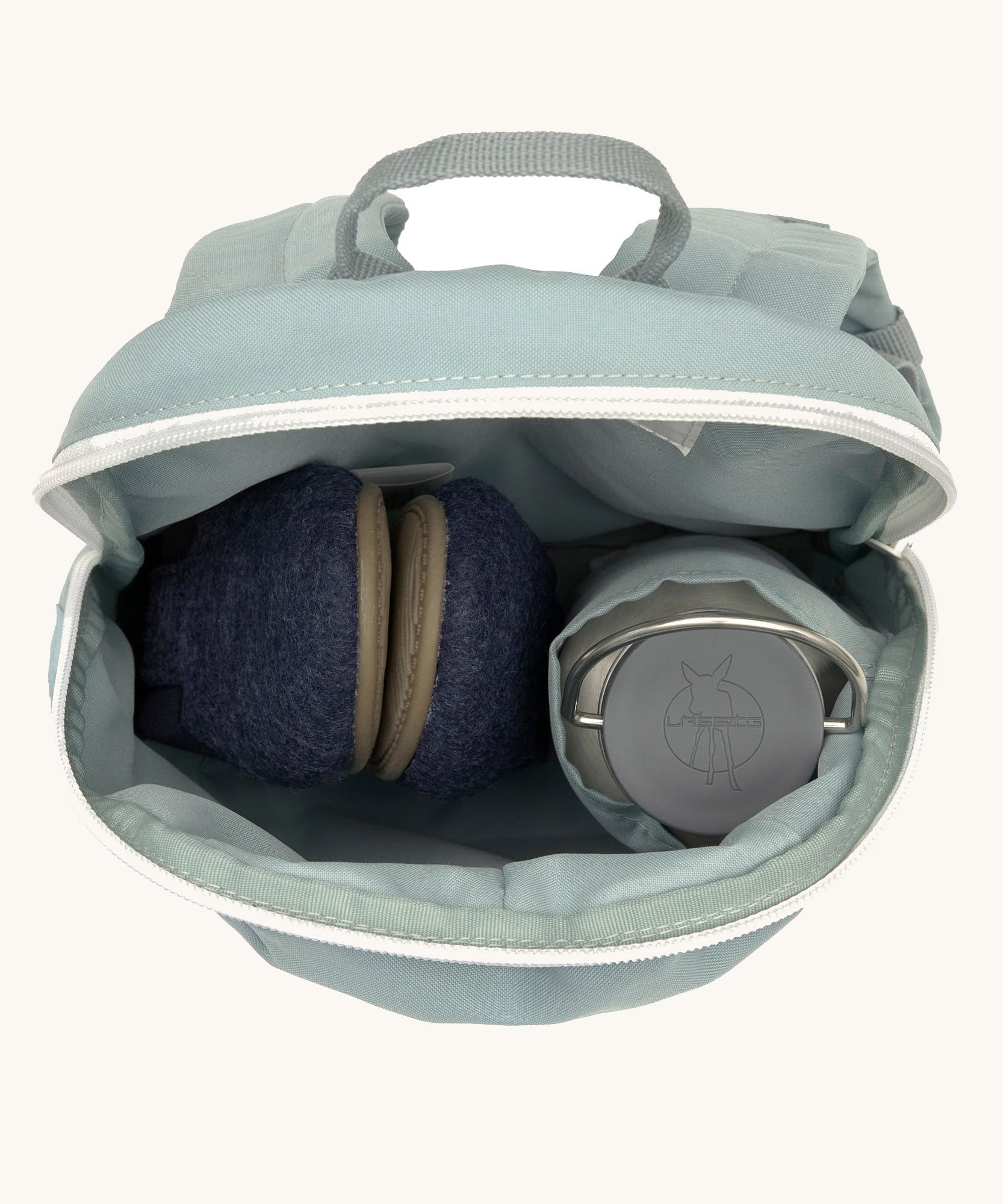 A close up of the Lassig kids tiny backpack in penguin showing the bottle holder detail and space inside the main compartment of the backpack