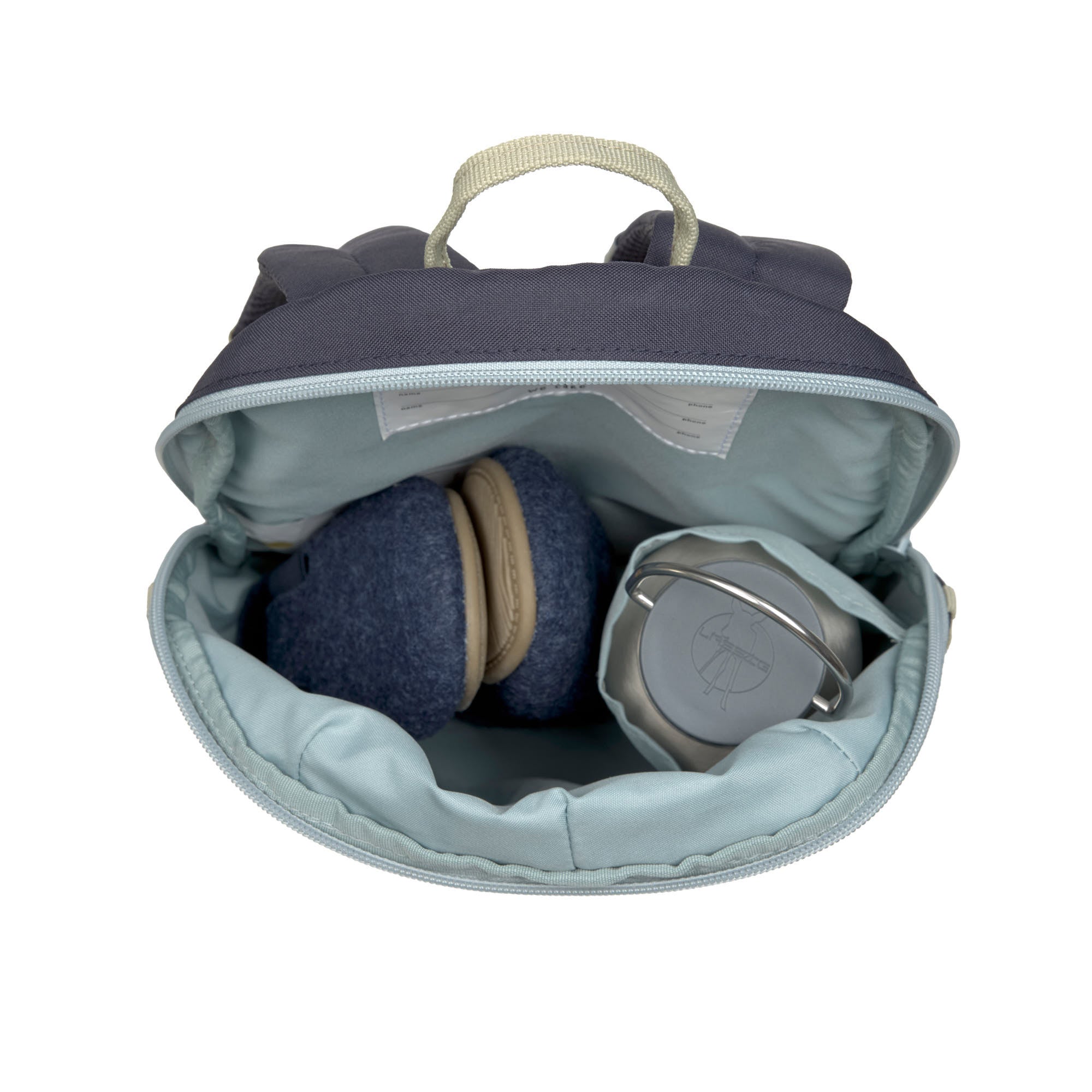 A top view of the Lassig tiny kids backpack, showing the storage space. Inside is a air of shoes and a water bottle.