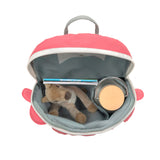 Lassig Kids Tiny Backpack in a bright coral colour with a dinosaur face, shown from a top angle to show the inside space. Inside is a water bottle, some books, and a soft cuddly toy.