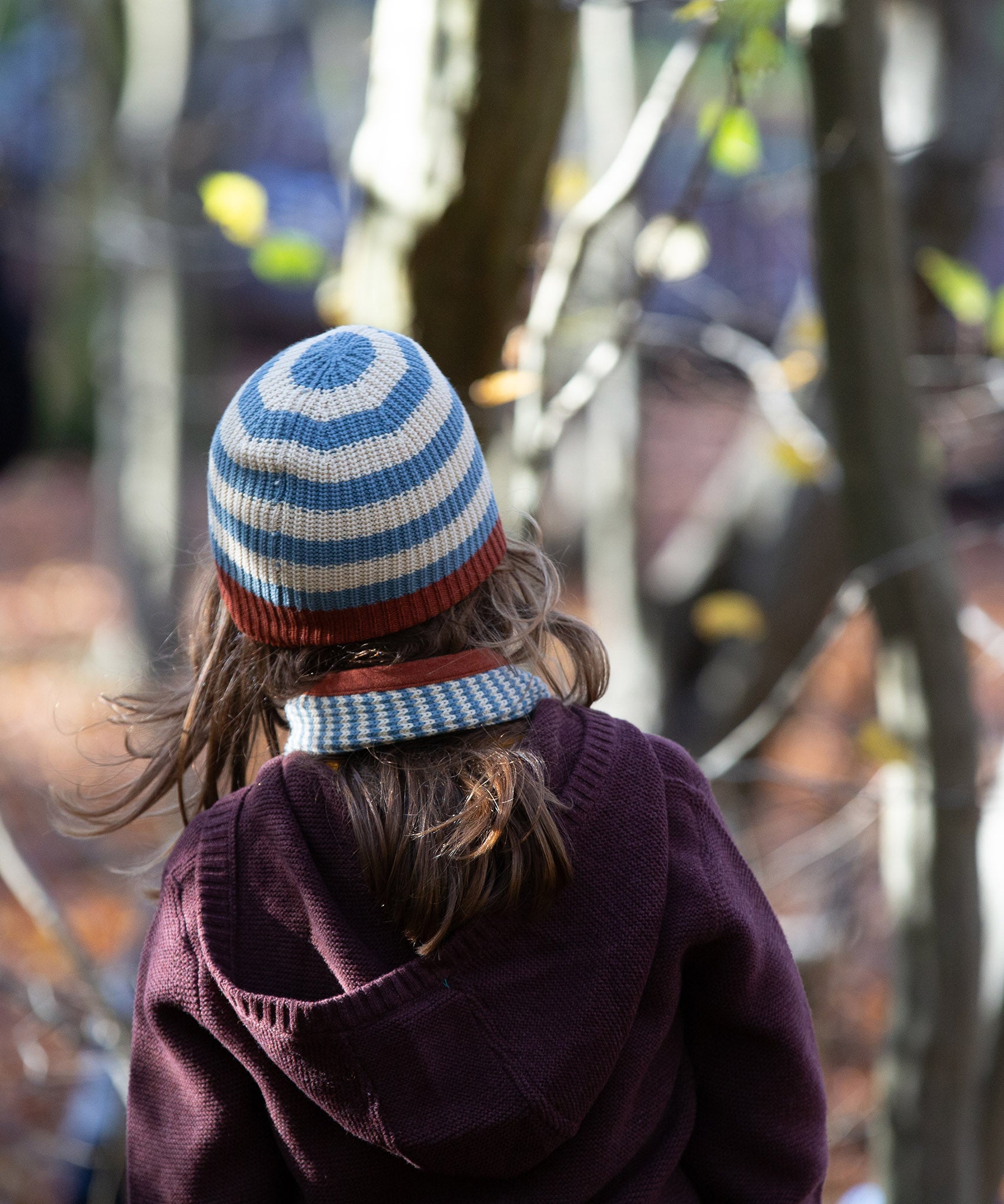 Back of child's head wearing a Little Green Radicals Fairtrade Knit Beanie in blue and cream stripes - made with GOTS organic cotton - shop now at Babipur.