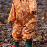 Baby playing in a forest wearing a Waterproof Winter Suit in Gold Ducks print, by Little Green Radicals, made from recycled bottles and a cosy polyester fleece, buy now at Babipur.