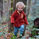 Boy running around a forest wearing Polar Fleece Jacket in ginger red by Little Green Radicals, made from recycled fleece, available now at Babipur.