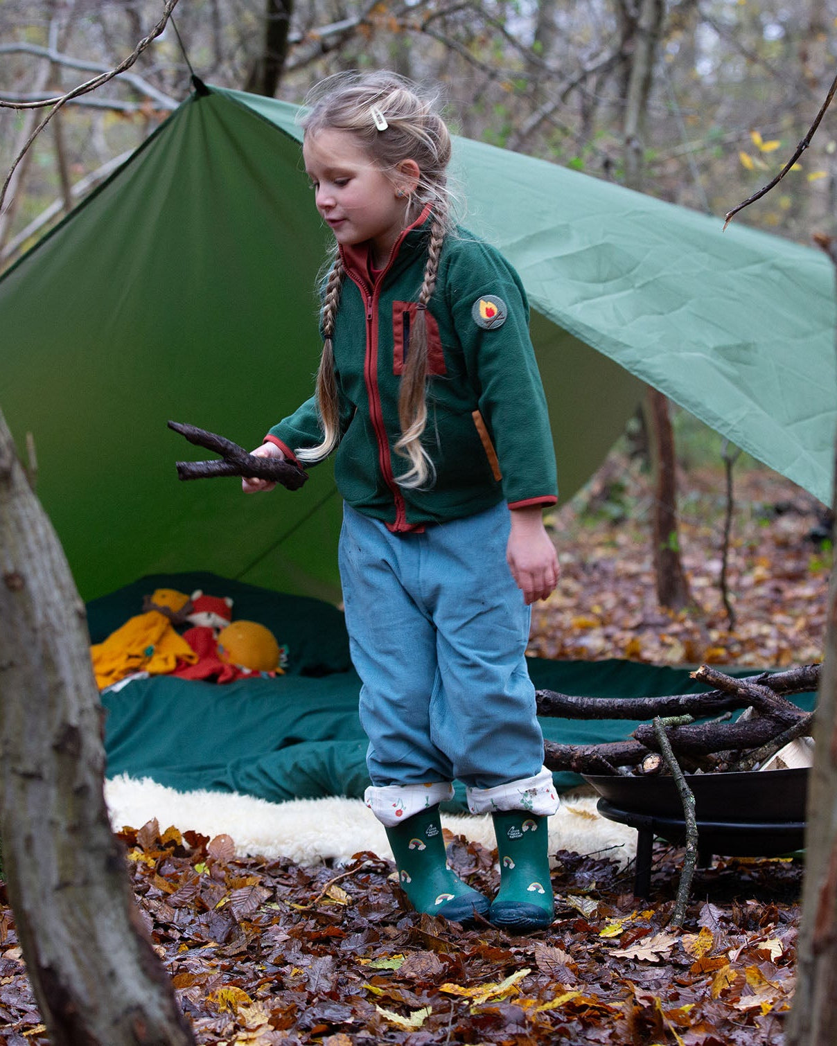 Girl camping in a forest wearing Little Green Radicals Kids Polar Fleece Jacket in Olive green with a red pocket and zip, buy now at Babipur.