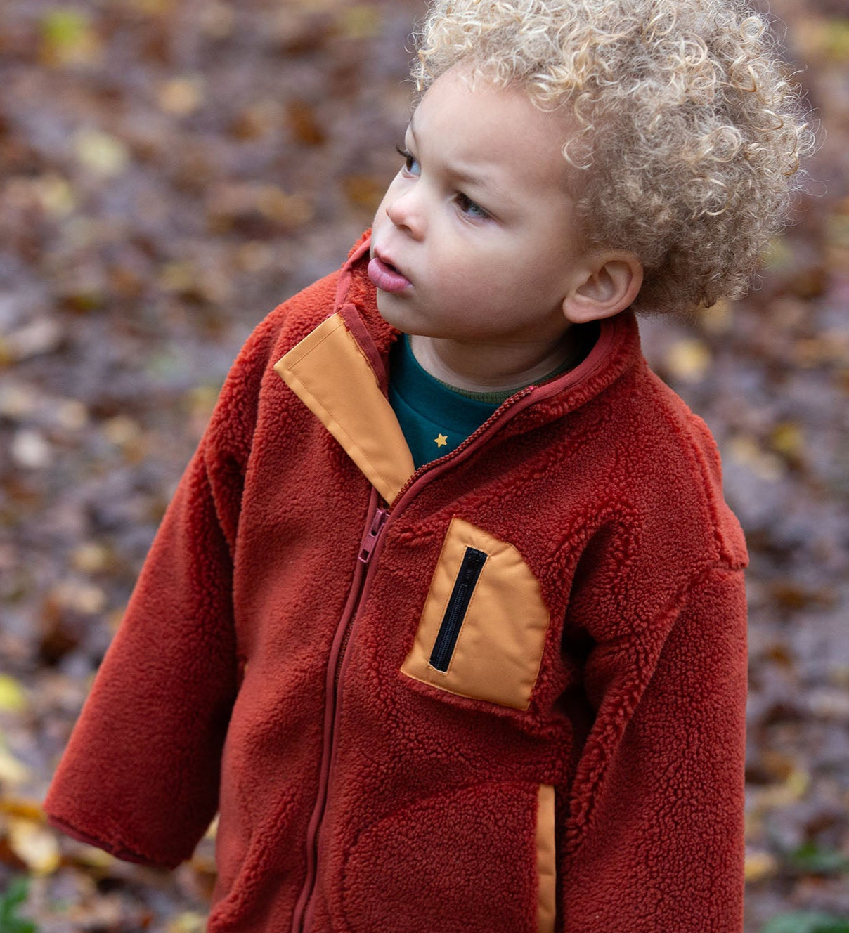 Child in a forest wearing Polar Fleece Jacket in Ginger red with a gold pocket by Little Green Radicals, made from recycled fleece, buy now at Babipur.