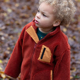 Child in a forest wearing Polar Fleece Jacket in Ginger red with a gold pocket by Little Green Radicals, made from recycled fleece, buy now at Babipur.