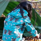 Back of girl playing in a forest wearing a hooded Little Green Radicals Waterproof Winter Coat, made from recycled bottles, with a turquoise Winter Rabbits print, for sale at Babipur.