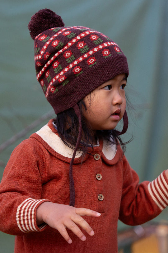 Child wearing Little Green Radicals Knitted Collar Dress in Ginger and a knitted collecting flowers hat to represent Little Green Radicals kids and baby clothing at Babipur.