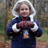 Child stood in a forest wearing brown and red floral Knitted Mittens by Little Green Radicals - made from soft GOTS organic and Fairtrade certified cotton - for sale at Babipur.