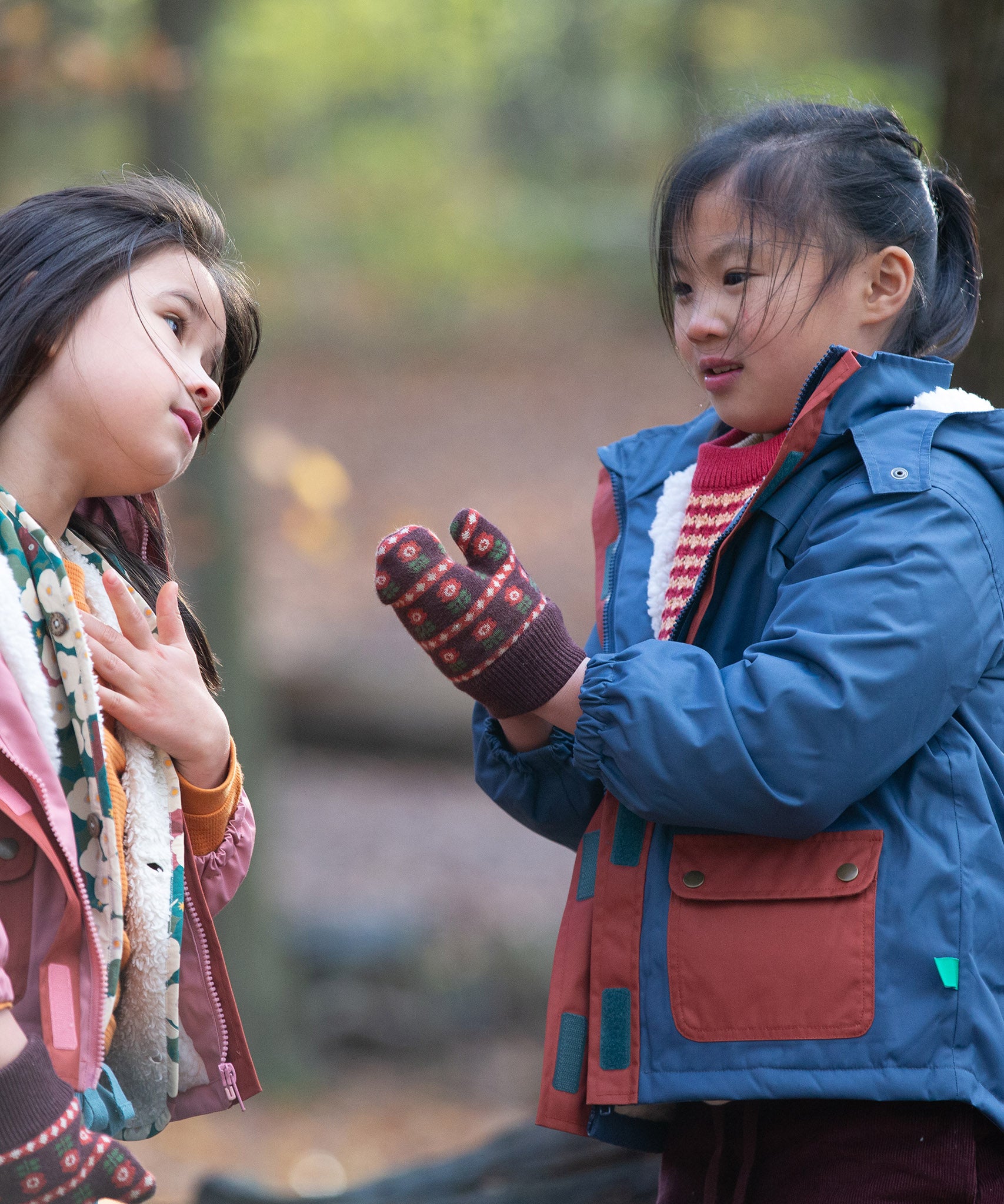 Child playing in a forest wearing a Long Sleeve Orange Ginger Knit Mittens by Little Green Radicals - made from soft GOTS organic and Fairtrade certified cotton - brown with red flowers, available to buy at Babipur.