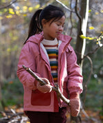 Child in a forest wearing Little Green Radicals Knitted Collar Mitten  in Ginger Diamons - made from warm GOTS organic and Fairtrade certified cotton - shop at Babipur.