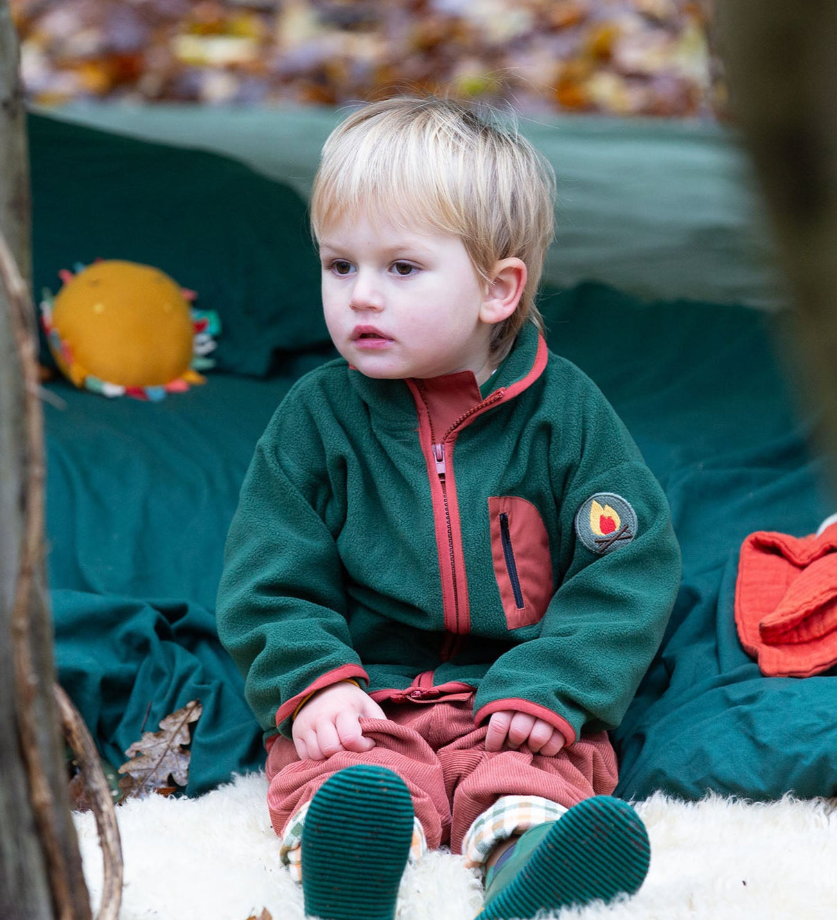 Child camping in a forest wearing Little Green Radicals Kids Polar Fleece Jacket in Olive - made from recycled polar fleece - available to buy at Babipur.