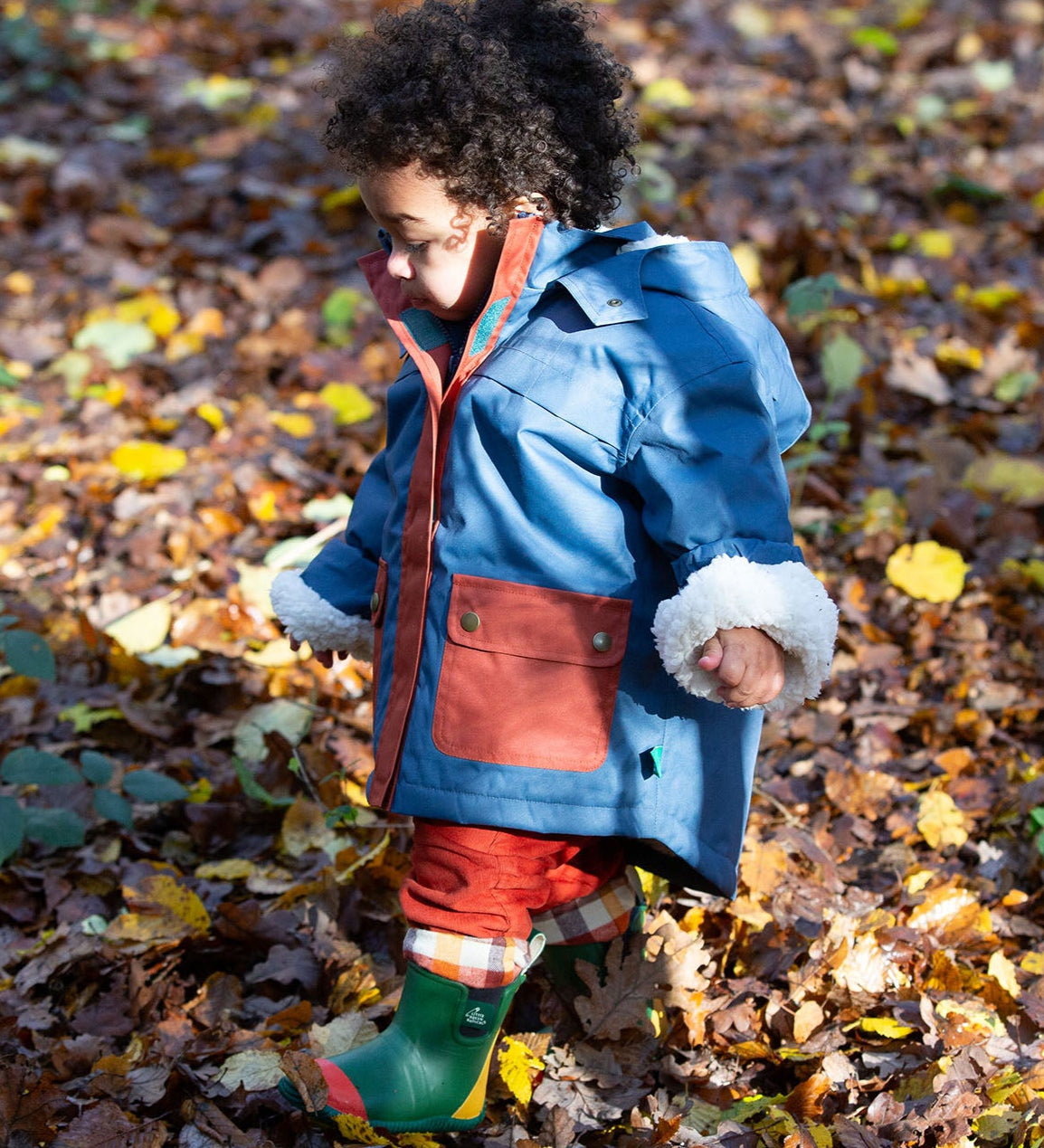 Baby in a forest wearing a Little Green Radicals PFC Free Waterproof Winter Coat with a cosy fleece hood, made from recycled bottles and a cosy polyester fleece, in a Moonlight Blue print, available now at Babipur.