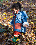 Baby in a forest wearing a Little Green Radicals PFC Free Waterproof Winter Coat with a cosy fleece hood, made from recycled bottles and a cosy polyester fleece, in a Moonlight Blue print, available now at Babipur.