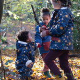 Baby in a forest wearing a Waterproof Winter Suit in Night Moon print, blue with stars, by Little Green Radicals, made from recycled bottles and a cosy polyester fleece, buy now at Babipur.
