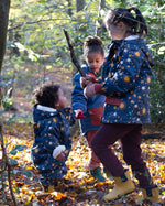 Baby in a forest wearing a Waterproof Winter Suit in Night Moon print, blue with stars, by Little Green Radicals, made from recycled bottles and a cosy polyester fleece, buy now at Babipur.