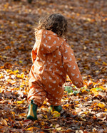 Back of baby playing in a forest wearing a Hooded Waterproof Winter Suit in Gold Ducks print, by Little Green Radicals, made from recycled bottles with and a cosy polyester fleece, with a pair of Fairtrade rubber wellies, available to buy at Babipur.