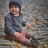A child sitting on a cobbled surface and wearing the Mamalila quilted Berlin booties in Khaki available at Babipur.