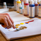 A close up of an artist holding a palette knife using the Natural Earth Paint acrylic paints on paper