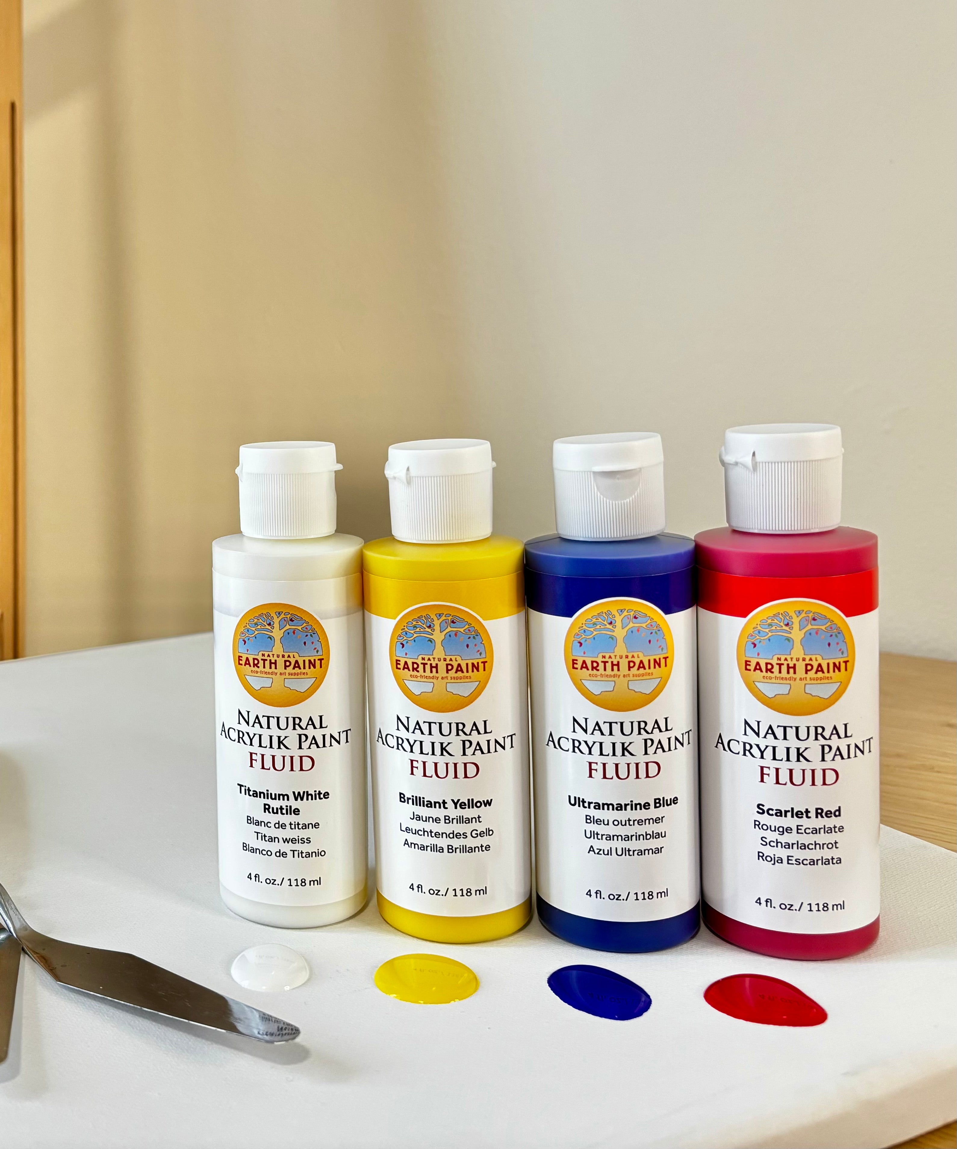 A set of the Natural Earth Paint on a canvas showing the titanium white, brilliant yellow, ultramarine blue and scarlet red colours.