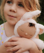 A close up of a girl holding the Olli Ella cozy dinkum bunny pip doll in pink showing the cute sleeping facial features. This fluffy toy doll is available at Babipur.