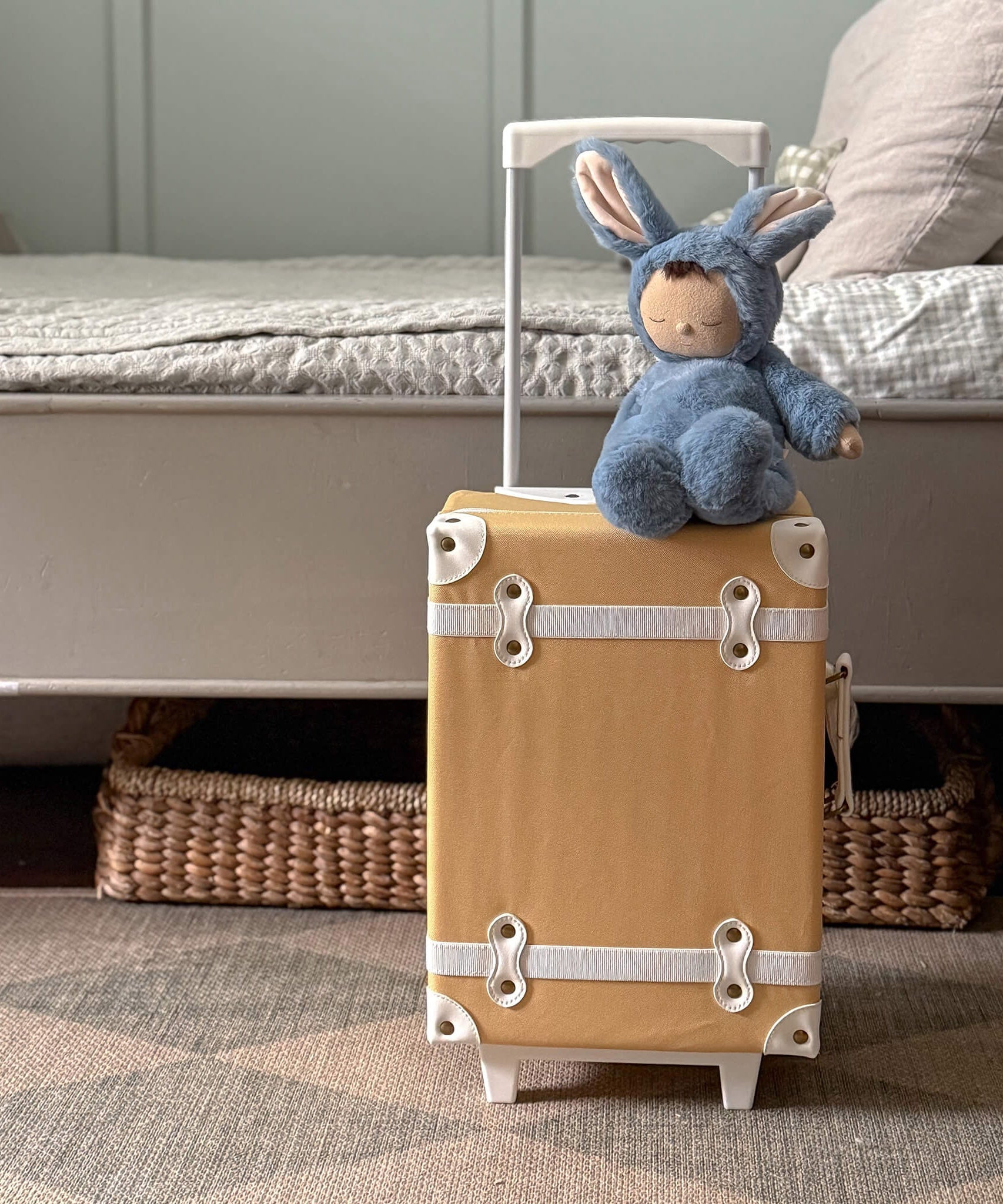 Olli Ella cozy dinkum bunny twiggy doll sitting on top of a Olli Ella suitcase in a bedroom. This fluffy toy doll is available at Babipur
