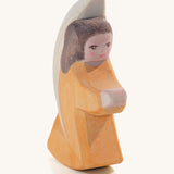 A wooden orange Ostheimer little angel figure on a cream background.